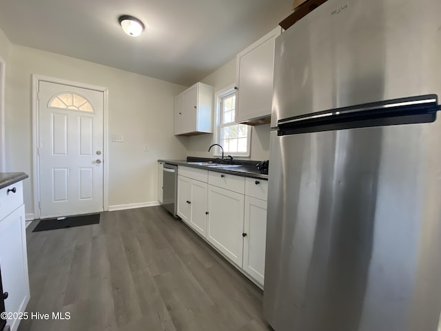 kitchen with dark countertops, white cabinets, stainless steel appliances, and a sink