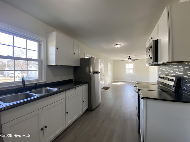 kitchen featuring appliances with stainless steel finishes, dark countertops, a sink, and tasteful backsplash