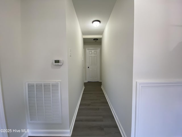 hall with baseboards, visible vents, and wood finished floors