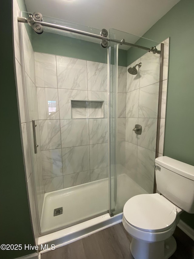 full bath featuring wood finished floors, a shower stall, and toilet