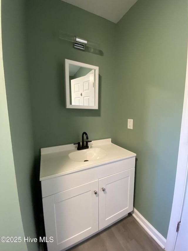 bathroom featuring baseboards, wood finished floors, and vanity