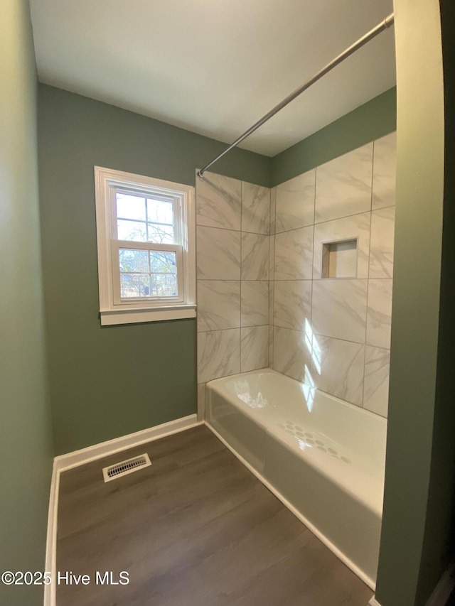 bathroom with shower / bath combination, visible vents, baseboards, and wood finished floors