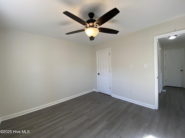 empty room featuring dark wood-type flooring and baseboards