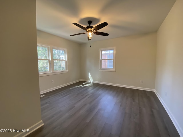 spare room with baseboards, dark wood finished floors, and a ceiling fan