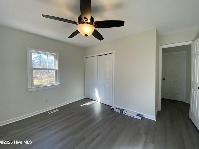 unfurnished bedroom featuring baseboards, a closet, visible vents, and dark wood-style flooring