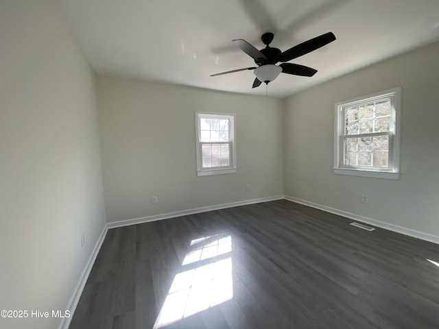 empty room featuring visible vents, baseboards, ceiling fan, and dark wood-type flooring