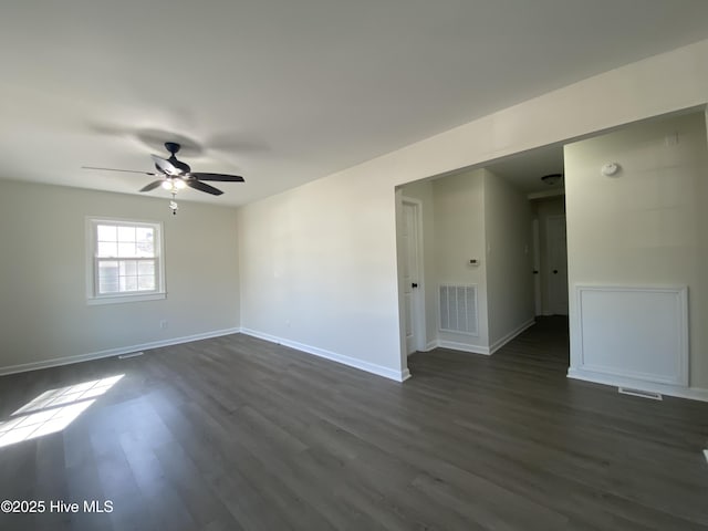 unfurnished room with dark wood-style floors, baseboards, visible vents, and ceiling fan