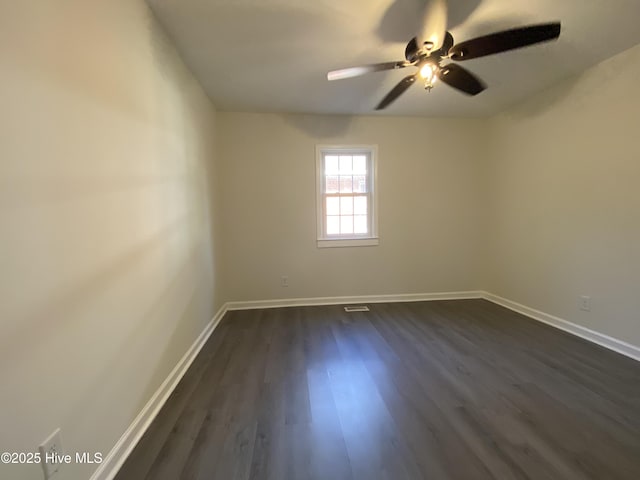 spare room featuring a ceiling fan, visible vents, baseboards, and dark wood-style flooring