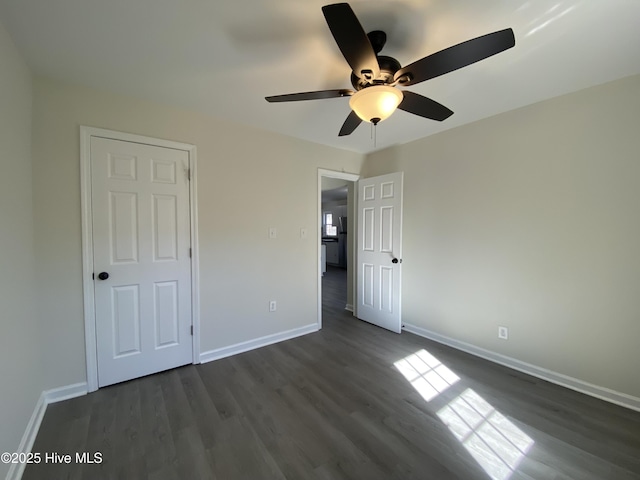 unfurnished bedroom with dark wood-style flooring, ceiling fan, and baseboards