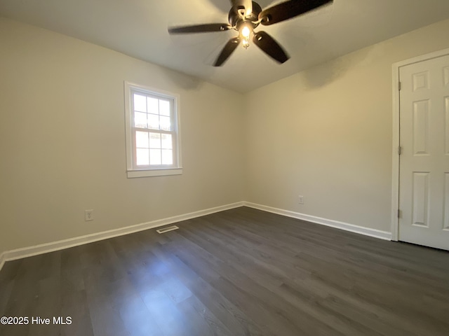 empty room with a ceiling fan, dark wood-style flooring, visible vents, and baseboards