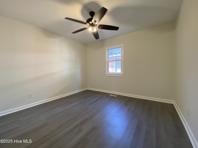 unfurnished room featuring a ceiling fan, dark wood-style flooring, visible vents, and baseboards