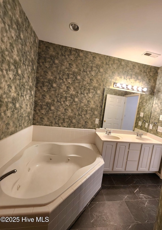 bathroom with a jetted tub, a sink, and wallpapered walls