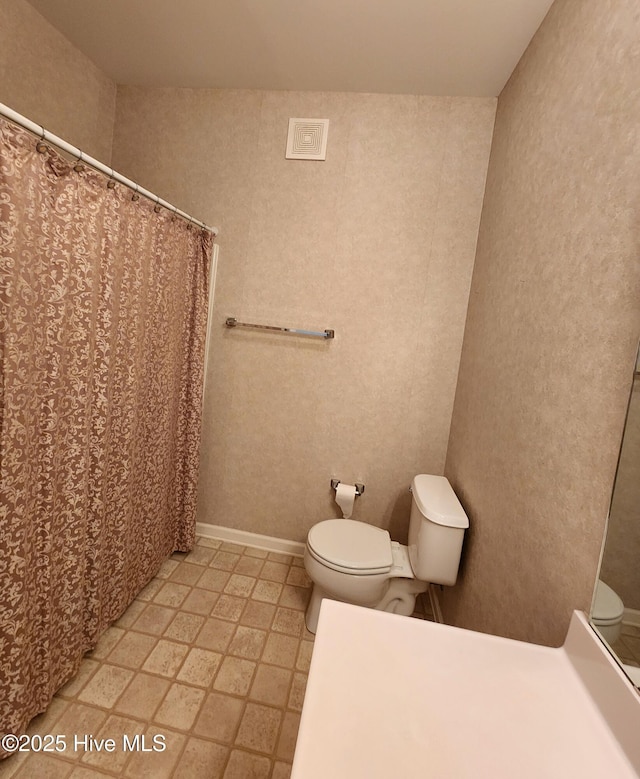 full bath featuring toilet, baseboards, and a shower with shower curtain