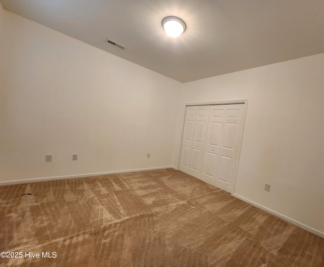 unfurnished bedroom featuring a closet, carpet, visible vents, and baseboards