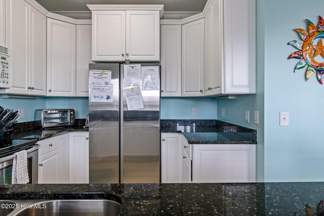 kitchen with appliances with stainless steel finishes, a toaster, and white cabinetry