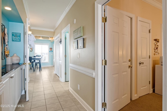 corridor featuring light tile patterned floors, baseboards, and crown molding