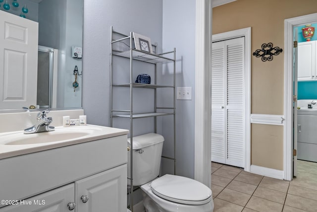 full bathroom with washer / dryer, toilet, tile patterned flooring, vanity, and a closet