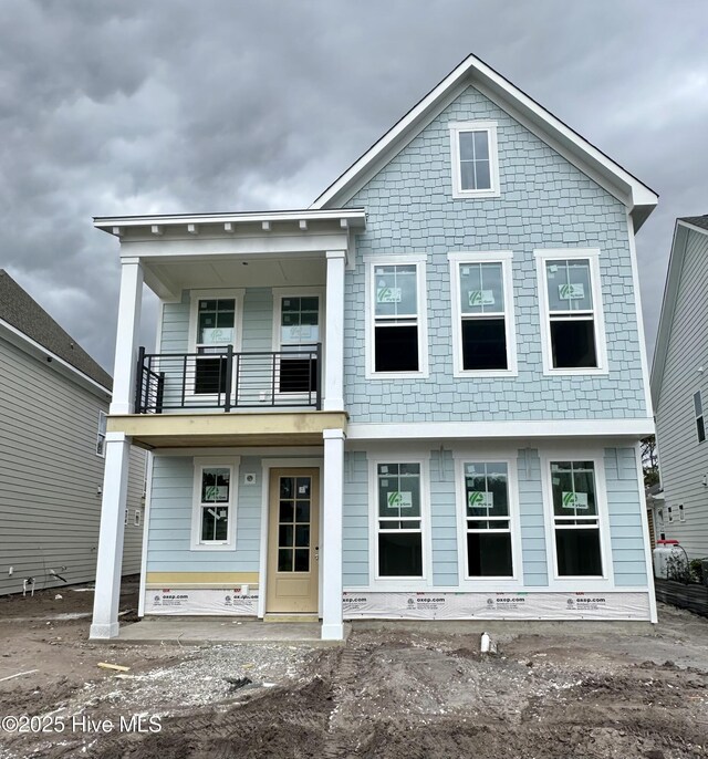 view of front of property with stone siding, a front yard, and a balcony