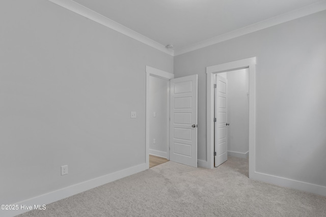 unfurnished bedroom featuring carpet, a spacious closet, baseboards, and crown molding