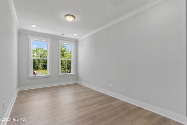 unfurnished room featuring baseboards, ornamental molding, attic access, and light wood-style floors