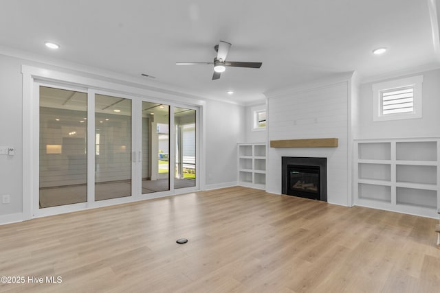 unfurnished living room with ornamental molding, a large fireplace, and light wood finished floors