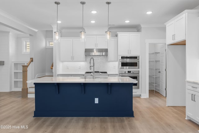 kitchen with a breakfast bar area, light wood-style flooring, stainless steel double oven, white cabinets, and under cabinet range hood