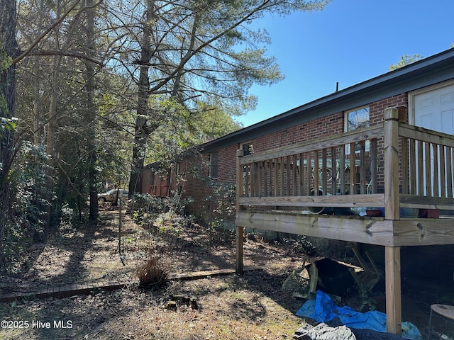 view of side of home featuring brick siding and a wooden deck