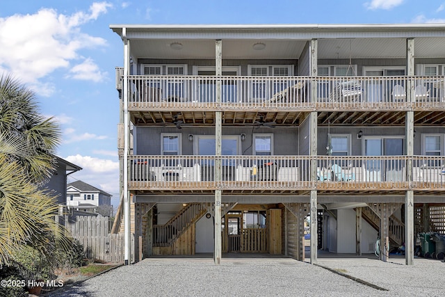 view of front facade featuring a carport, gravel driveway, fence, and stairs