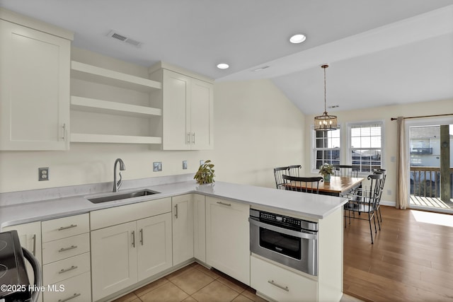 kitchen with visible vents, stove, a sink, oven, and a peninsula