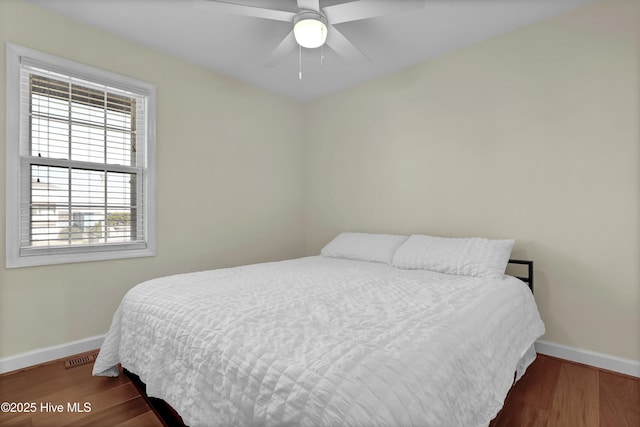 bedroom with visible vents, baseboards, ceiling fan, and wood finished floors