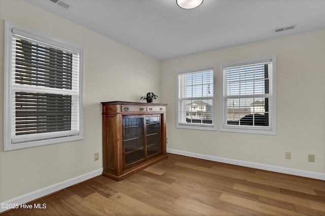 spare room with visible vents, baseboards, and wood finished floors