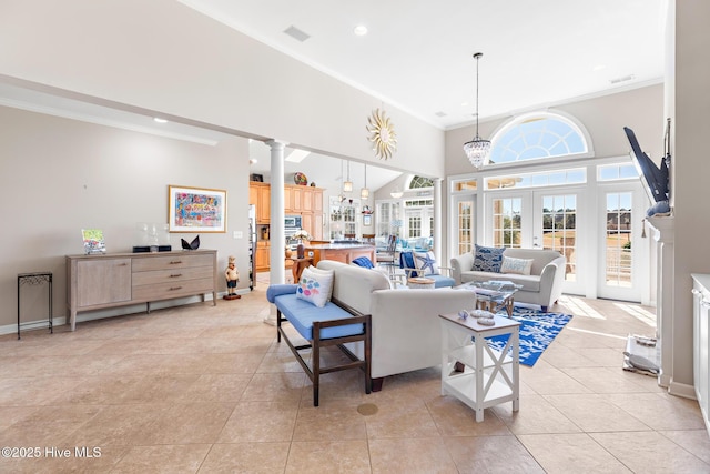 living room with a high ceiling, crown molding, ornate columns, and light tile patterned floors