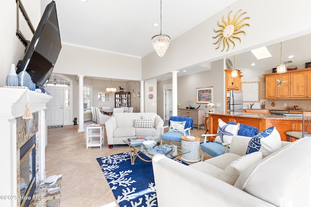 living room featuring crown molding, light tile patterned floors, decorative columns, and an inviting chandelier