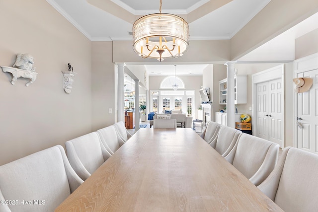 dining room with ornamental molding, a raised ceiling, decorative columns, and an inviting chandelier