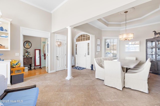 dining area featuring a tray ceiling, decorative columns, light tile patterned floors, a towering ceiling, and ornamental molding