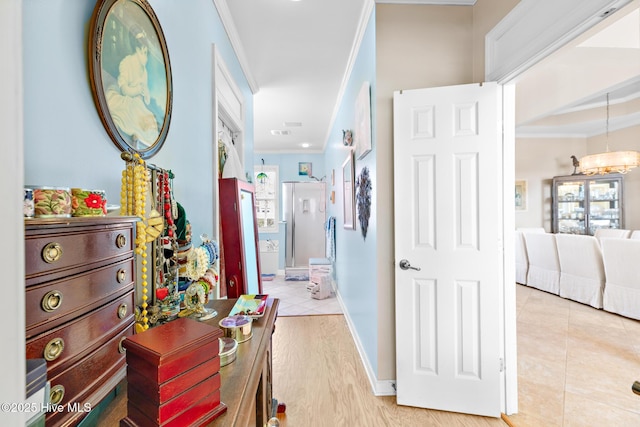 hall featuring baseboards, ornamental molding, light wood-style floors, and a notable chandelier