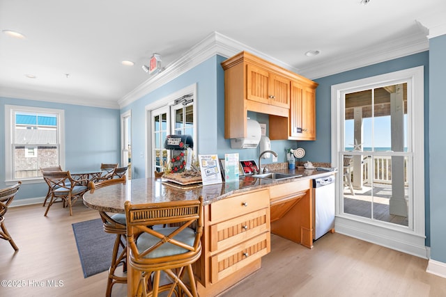 kitchen featuring crown molding, light wood-style flooring, stainless steel dishwasher, a sink, and baseboards