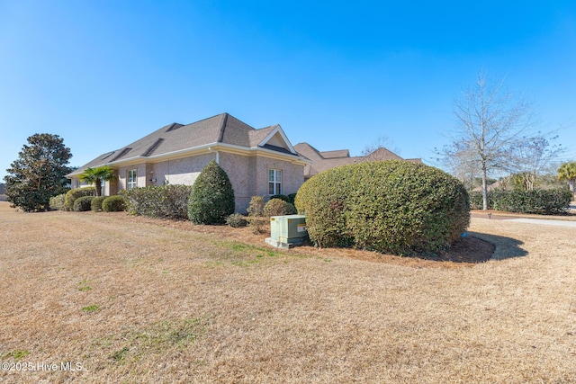 view of side of home featuring brick siding and a yard