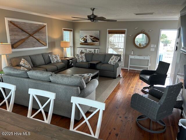 living room featuring a healthy amount of sunlight, wood-type flooring, visible vents, and crown molding