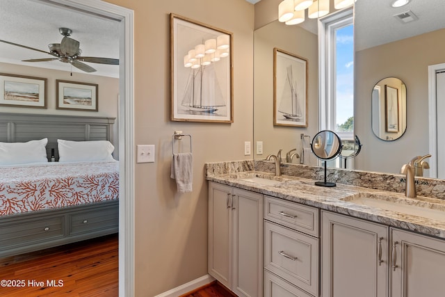 ensuite bathroom with double vanity, wood finished floors, a sink, and visible vents