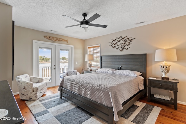 bedroom featuring access to outside, visible vents, wood finished floors, and french doors