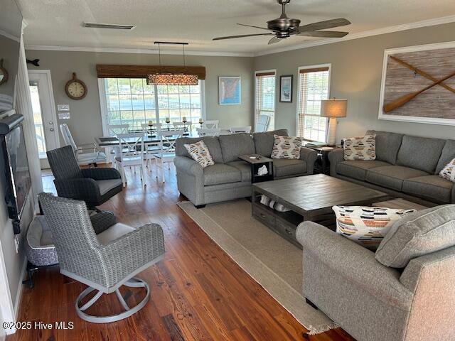 living room with a ceiling fan, crown molding, and wood finished floors