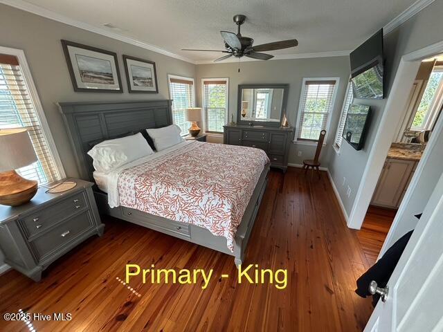 bedroom featuring crown molding, dark wood finished floors, baseboards, and ceiling fan