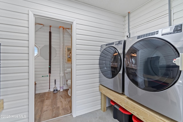 laundry area featuring wood walls and separate washer and dryer