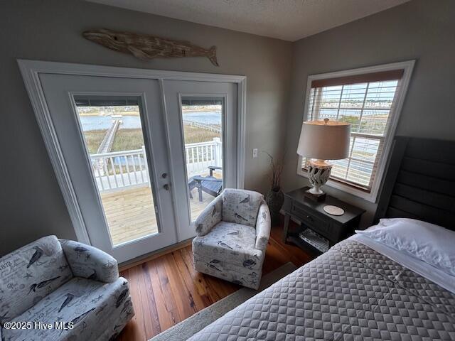 bedroom featuring a textured ceiling, multiple windows, wood finished floors, and access to exterior