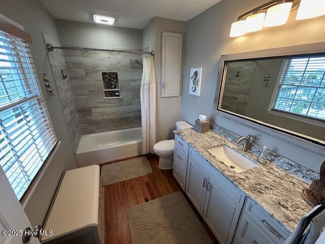 bathroom featuring vanity, shower / bath combination with curtain, wood finished floors, and toilet