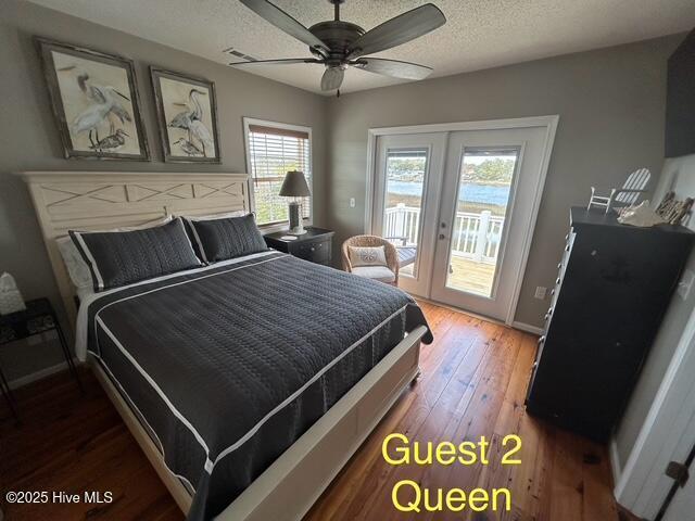 bedroom featuring access to exterior, french doors, a textured ceiling, wood finished floors, and baseboards