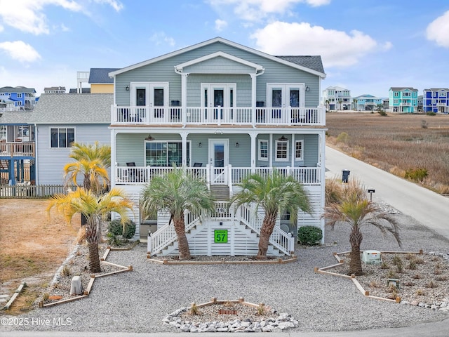 raised beach house featuring french doors, a porch, and a balcony