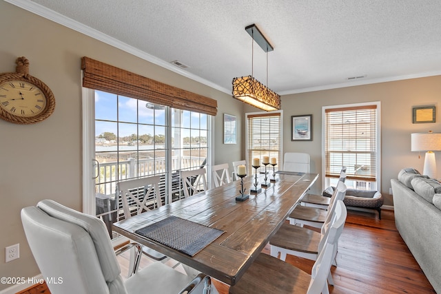 dining room with visible vents, crown molding, a textured ceiling, and wood finished floors