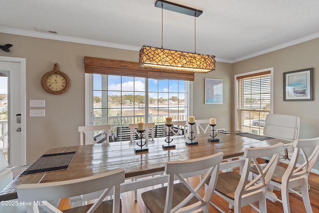 dining room with ornamental molding, visible vents, and wood finished floors